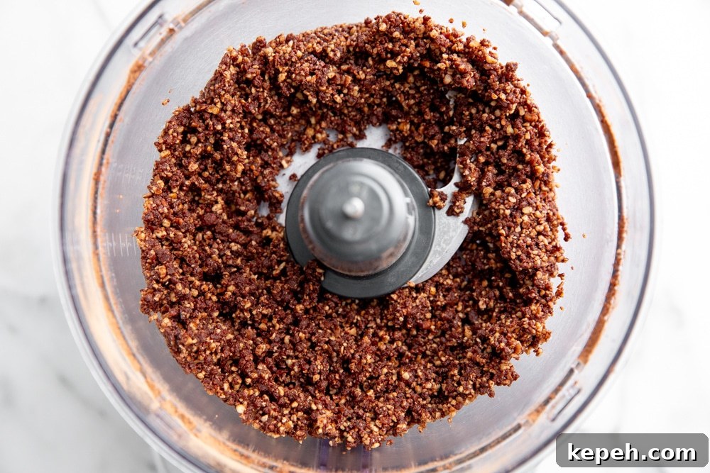 Process shot showing the chopped ingredients for the date nut crust in a food processor.