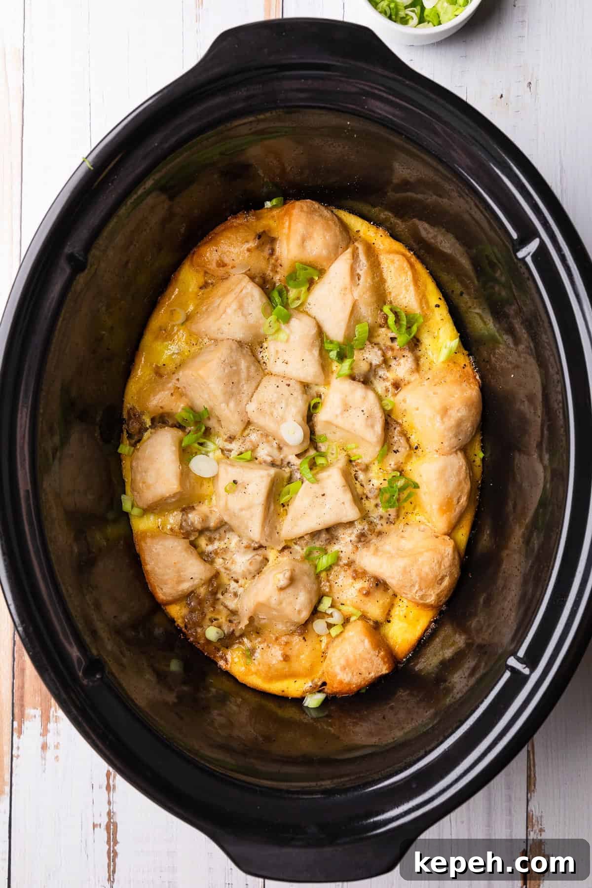 Crockpot Biscuits and Sausage Gravy Casserole 2 Crockpot of biscuits and gravy casserole with green onions.