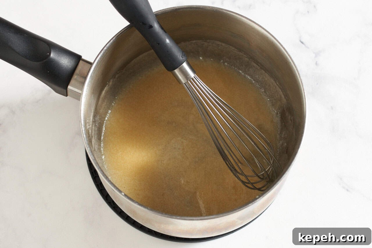 Roux in a sauce pan with a whisk in it.