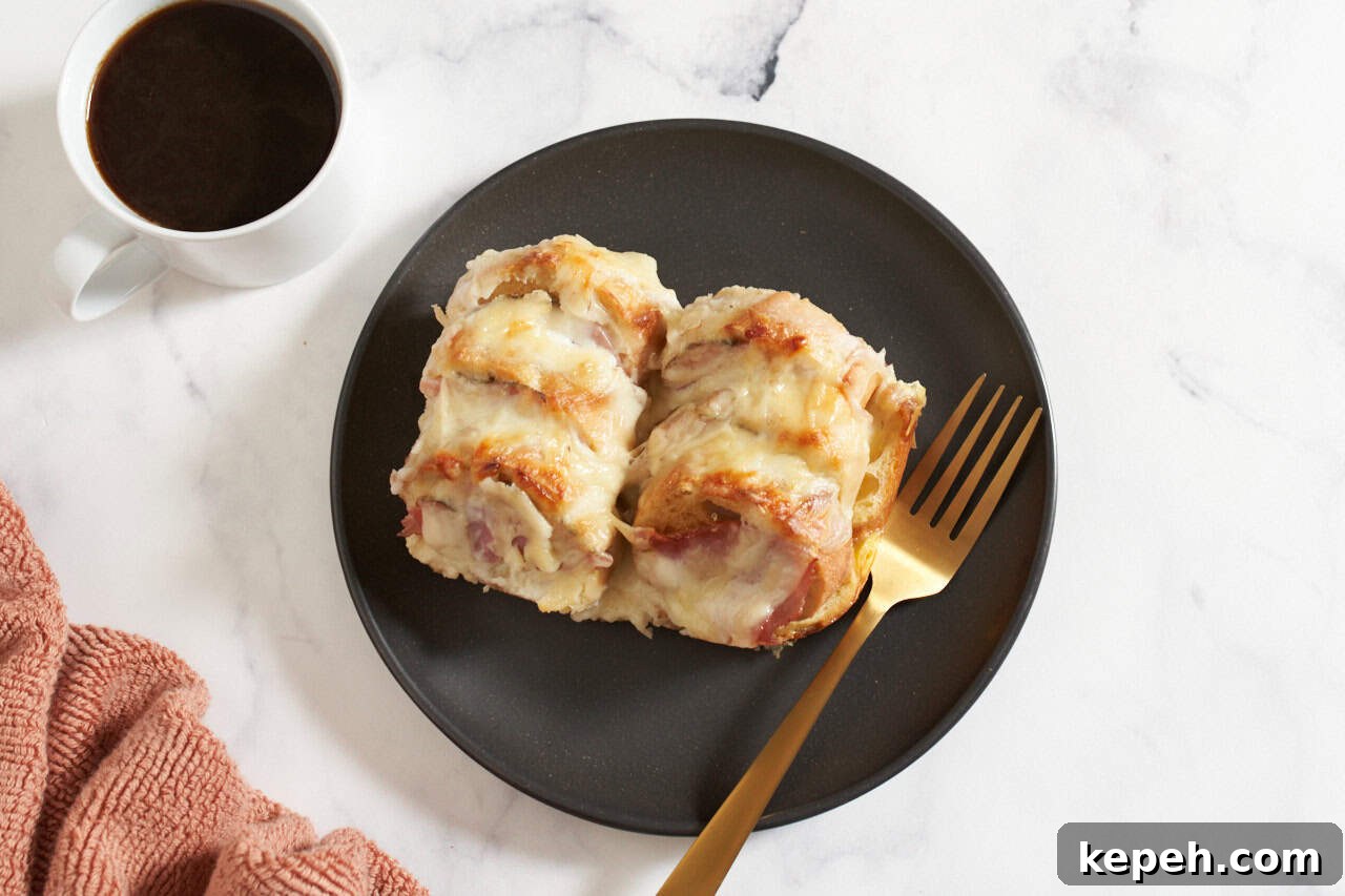 Croque monsieur breakfast casserole on a black plate with a gold fork, a cup of coffee is on the left.