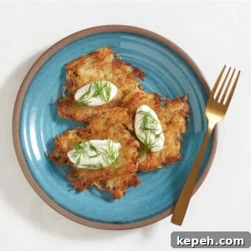 Ukrainian potato pancakes (deruny) topped with sour cream and dill on a blue plate, a gold fork is on the right.