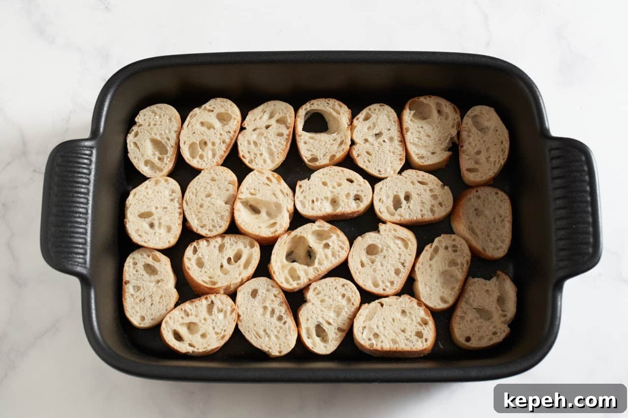 Baguette slices in a black casserole dish.