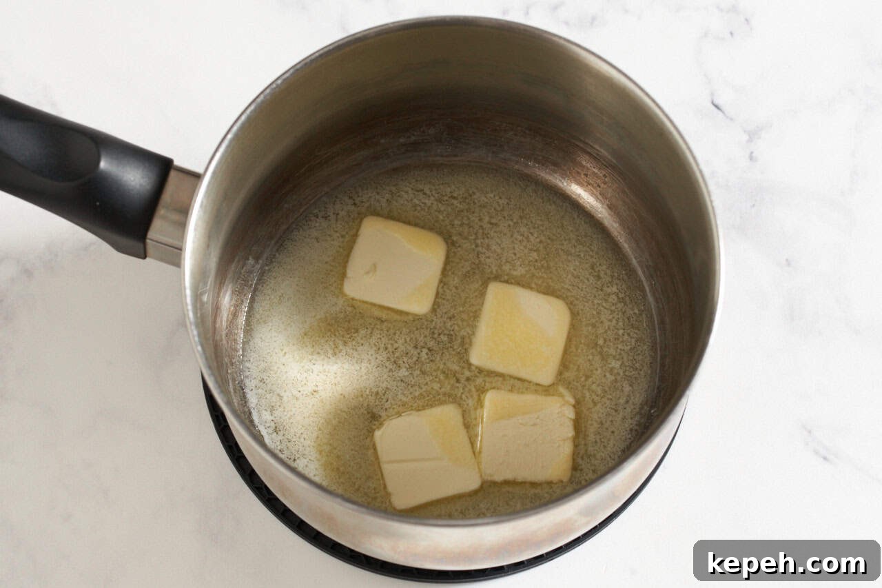 Four pats of butter melting in a sauce pan.