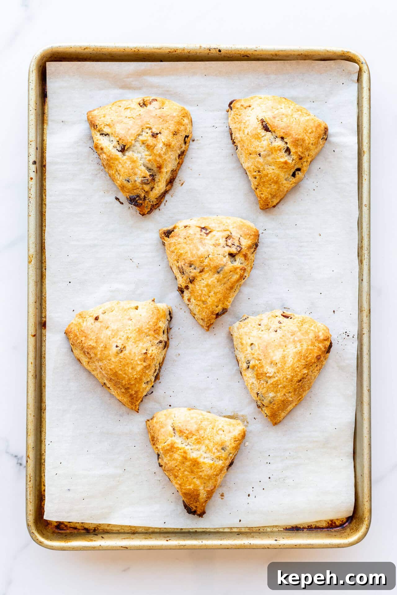 Chewy Date Scones with Honey Glaze 6 Parchment-lined sheet pan with 6 triangle wedge fruit scones, unglazed