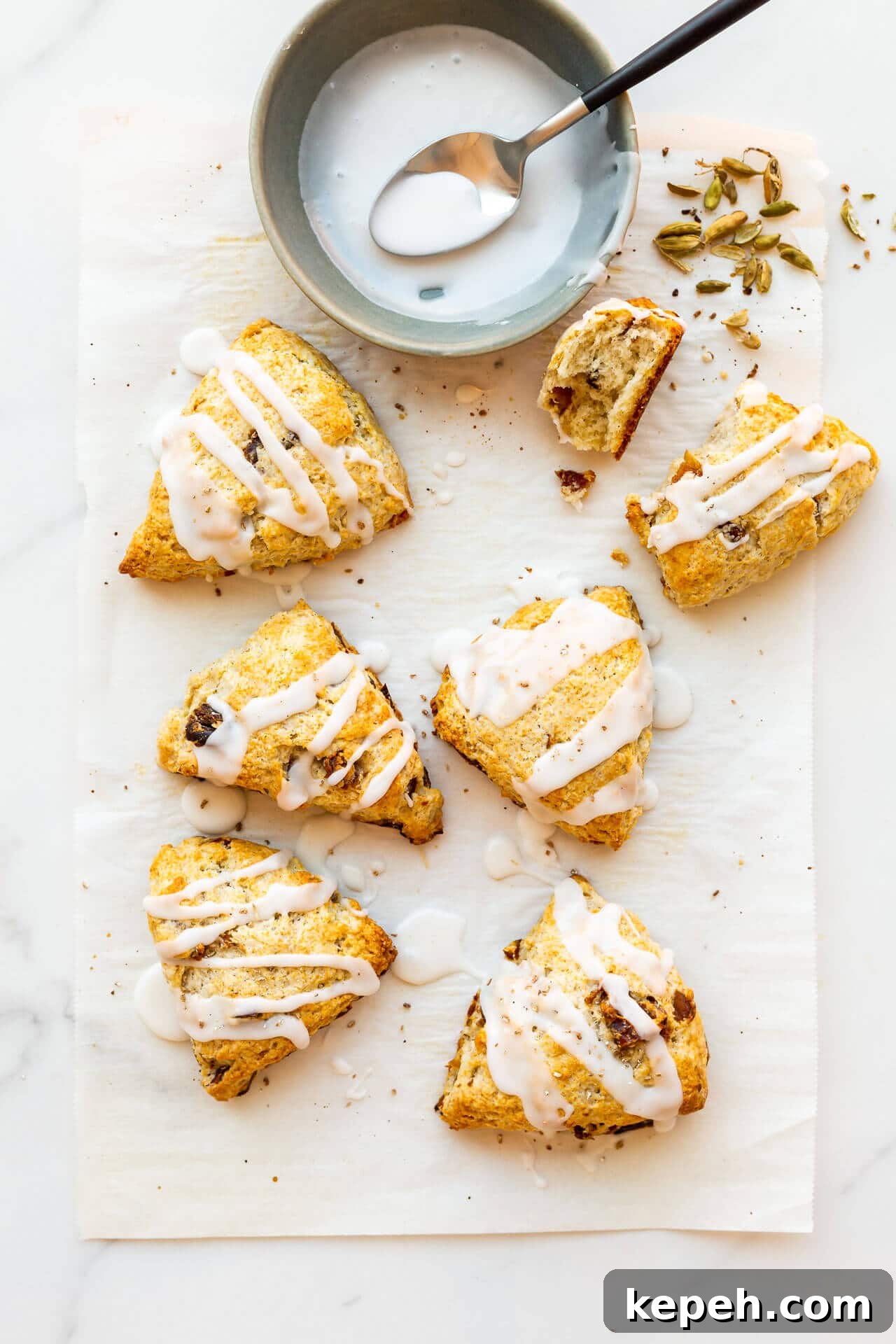 Chewy Date Scones with Honey Glaze 7 Six (6) glazed fruit scones with icing drizzled on from a bowl with a spoon, sprinkled with freshly ground cardamom from pods