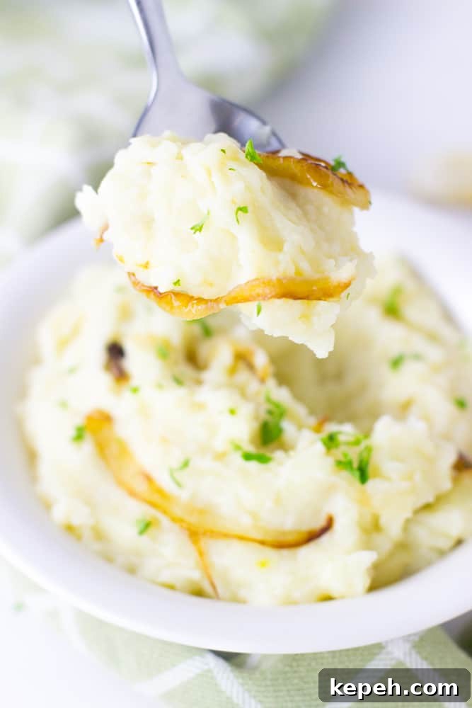 Spoon scooping out mashed potatoes from a white bowl.