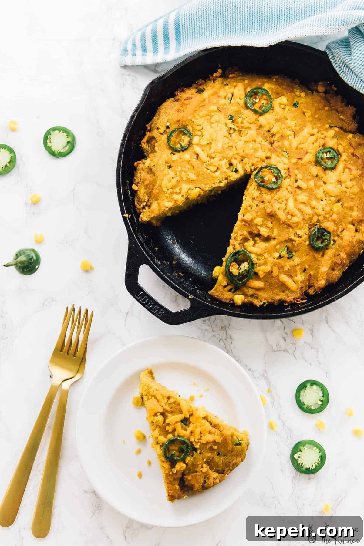Overhead view of cornbread in a skillet with a slice on a plate. 