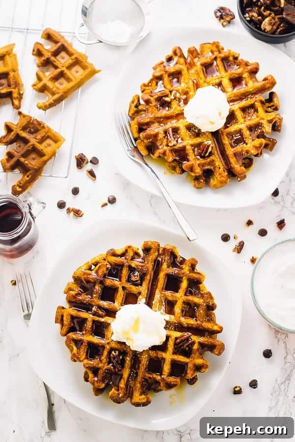 Overhead view of waffles on square white plates. 