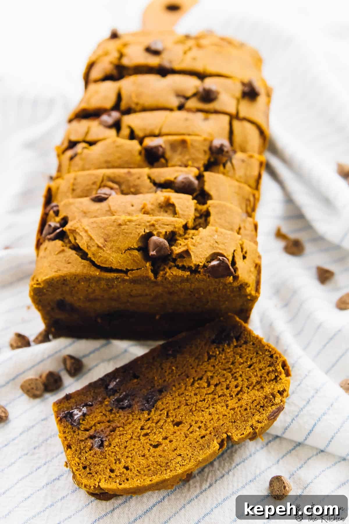 Slices of chocolate chip pumpkin bread on a striped cloth. 