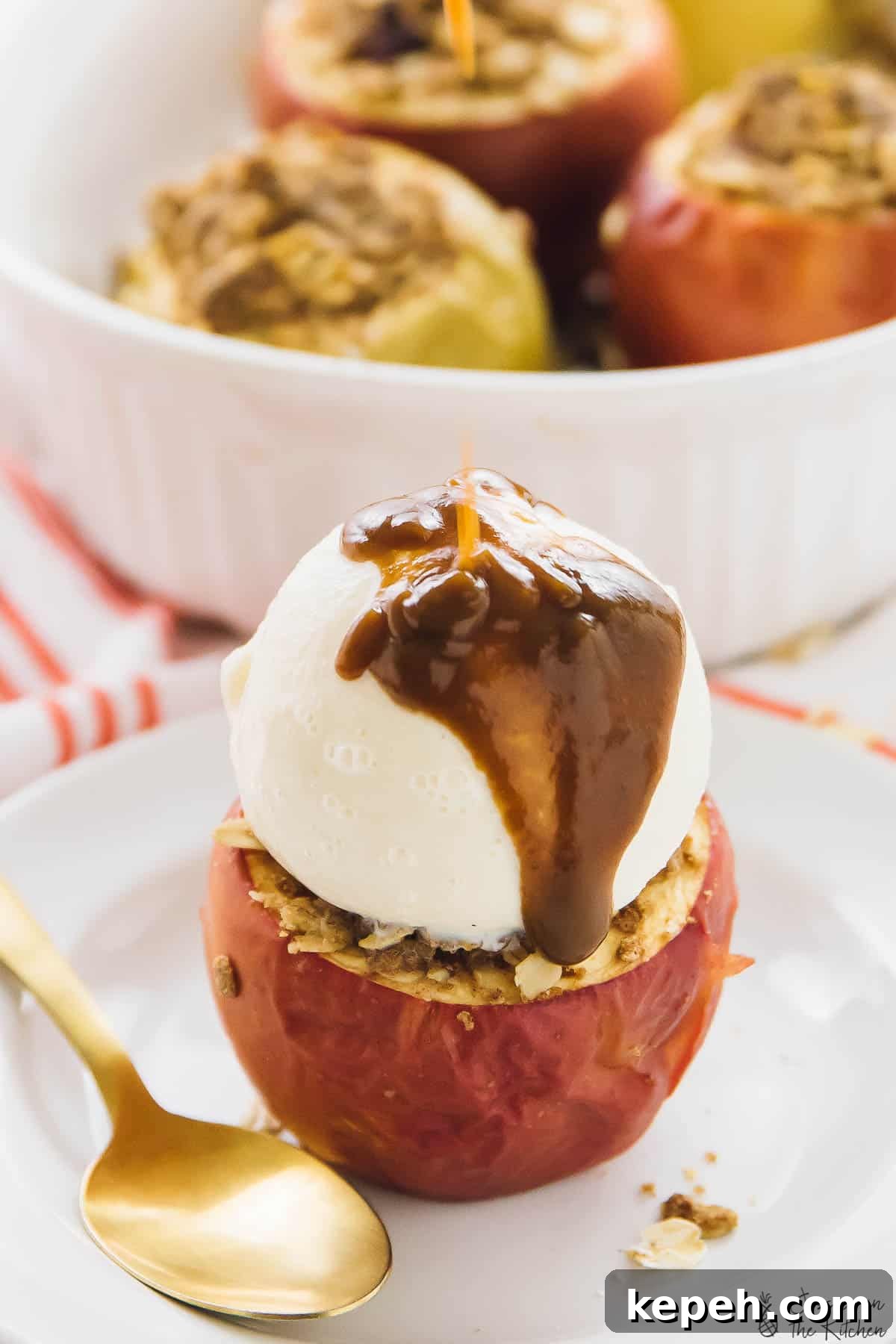 A baked apple topped with ice cream and a gold spoon on the side. 