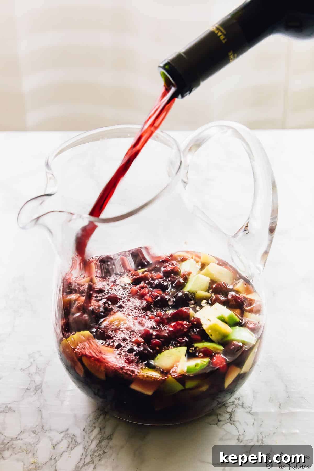 Red wine being poured into a jug of sangria. 