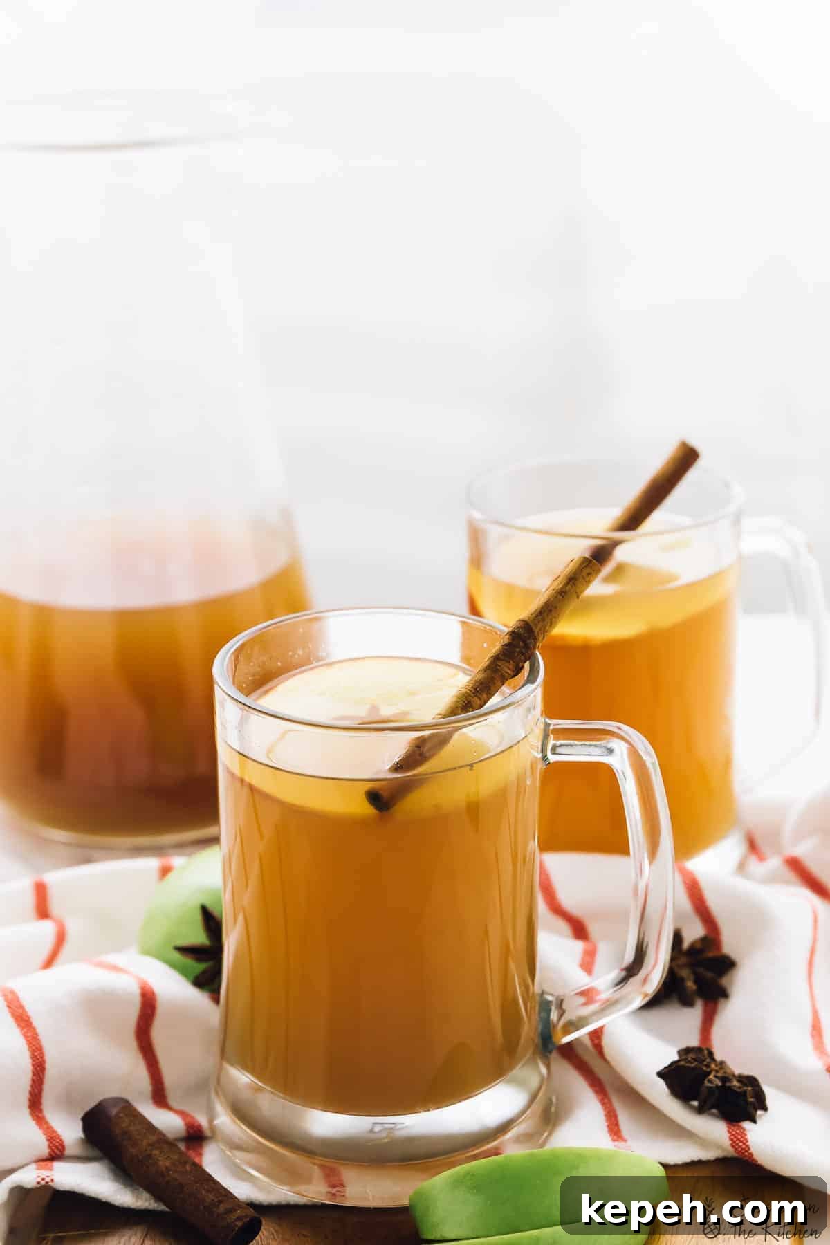 Two glass mugs of warm apple cider. 