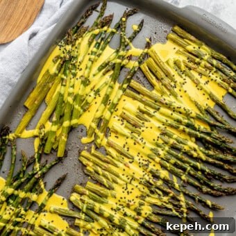 Roasted Asparagus with Lemon Cardamom Cream Sauce 11 Roasted asparagus on a sheet pan topped with a bright yellow lemon cardamom sauce and black sesame seeds.