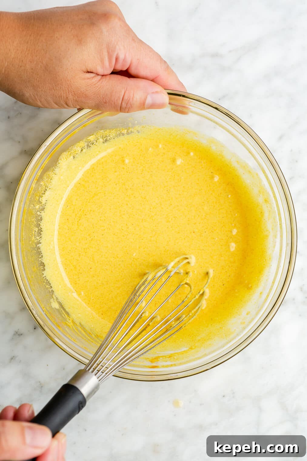 Roasted Asparagus with Lemon Cardamom Cream Sauce 7 A person whisking lemon cardamom sauce in a large glass bowl.