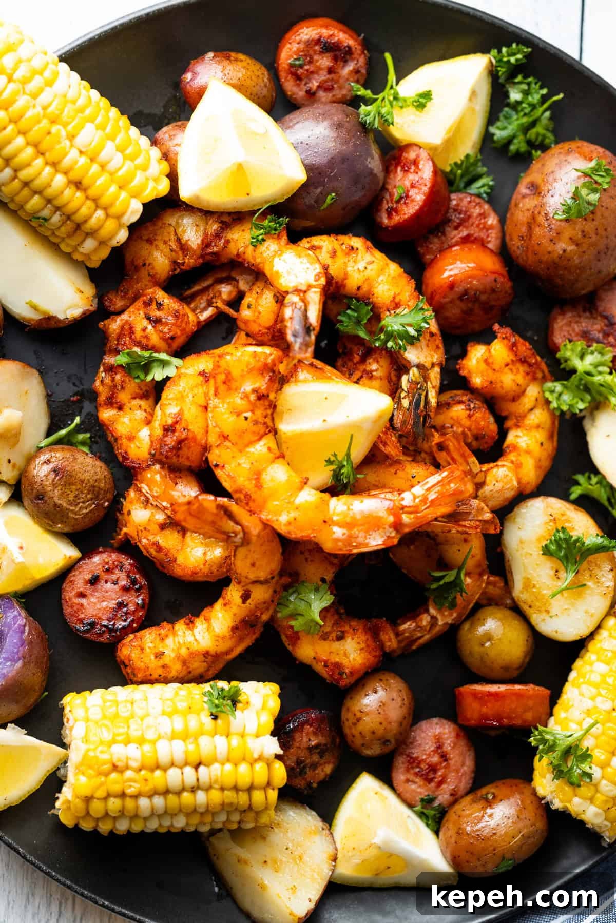How to Smoke Shrimp Perfectly: Simple Steps for Juicy Flavor 2 Smoked shrimp on a black plate surrounded by corn, potatoes, and lemon slices.
