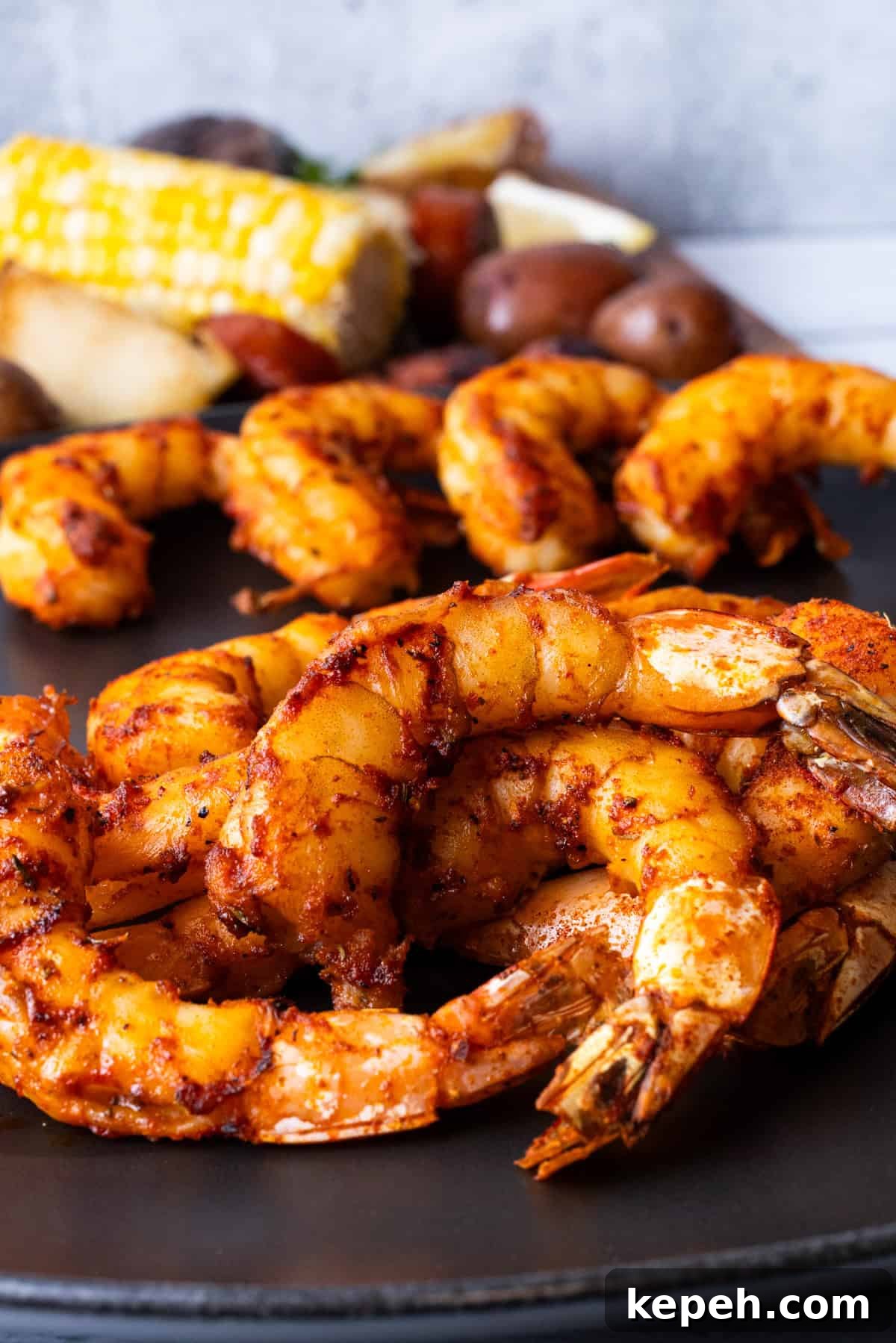How to Smoke Shrimp Perfectly: Simple Steps for Juicy Flavor 14 Smoked shrimp on black plate with corn on the cob in background.