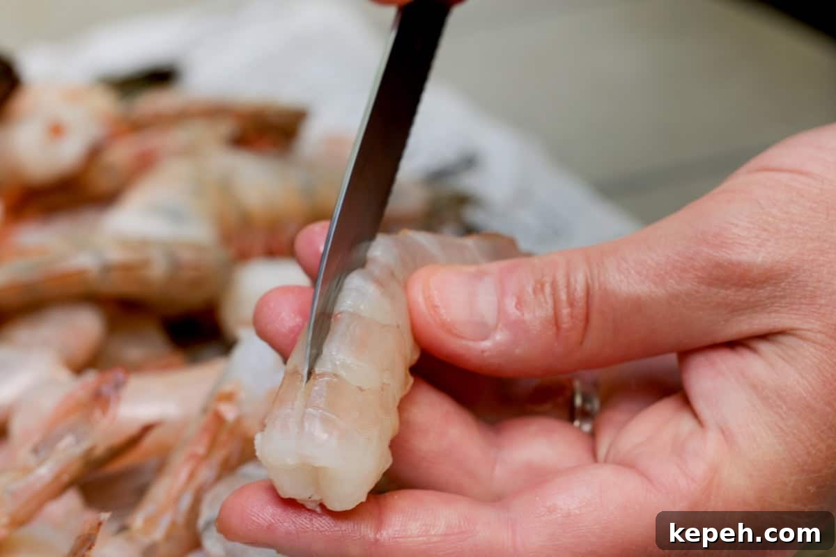 How to Smoke Shrimp Perfectly: Simple Steps for Juicy Flavor 4 Slicing down the back of a shrimp with knife. Plate of shrimp in background.