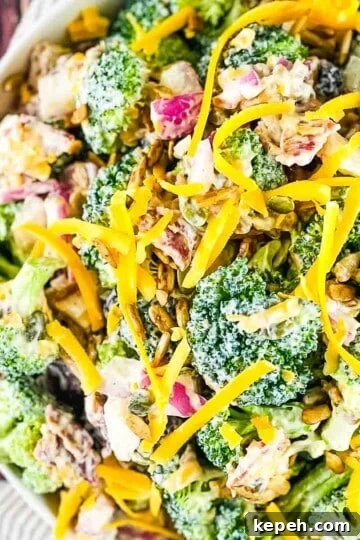 A serving bowl full of broccoli crunch salad garnished with shredded cheese.