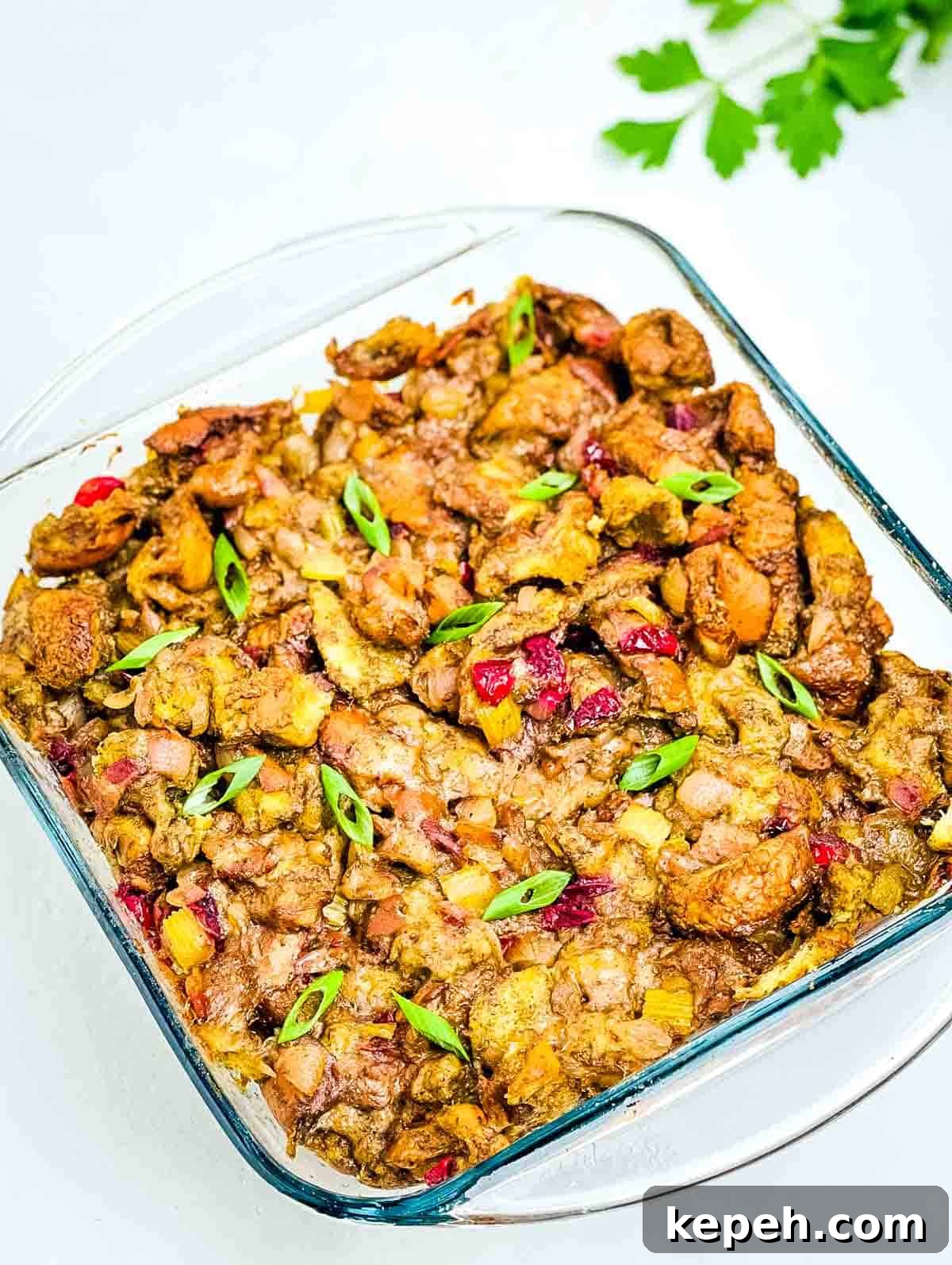 Bacon and Cranberry Stuffing Recipe for Holiday Tables 10 The crispy homemade stuffing in a glass baking dish, garnished with diced green onion.