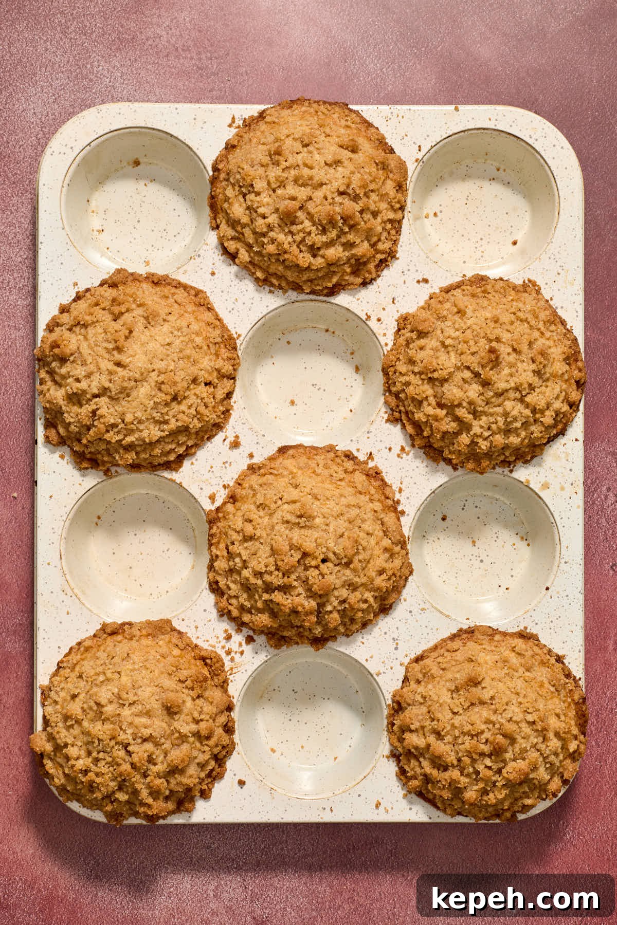 Spiced Eggnog Muffins with Streusel and Eggnog Glaze Recipe 12 Baked muffins in a white muffin tin.