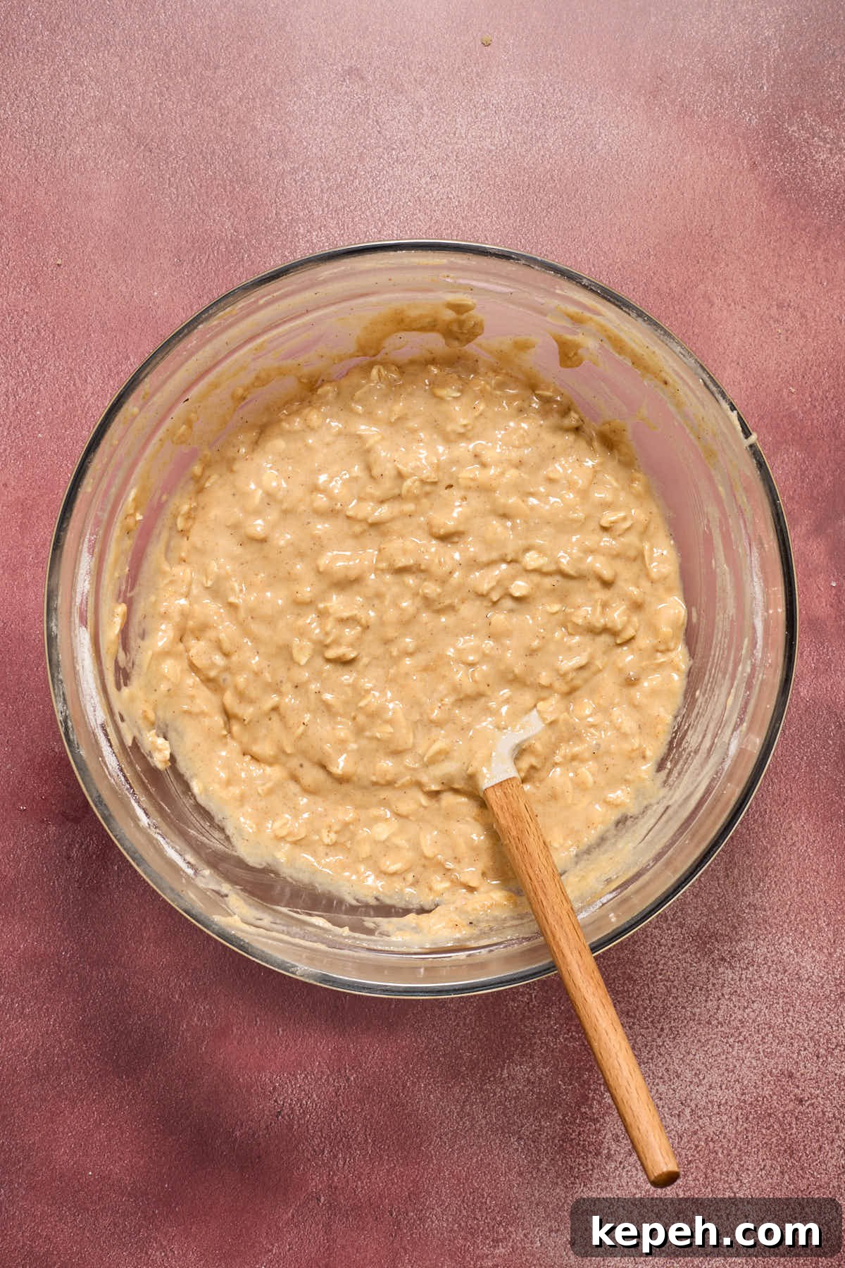 Spiced Eggnog Muffins with Streusel and Eggnog Glaze Recipe 8 Muffin batter mixed together in a glass bowl with a spatula inserted into it.