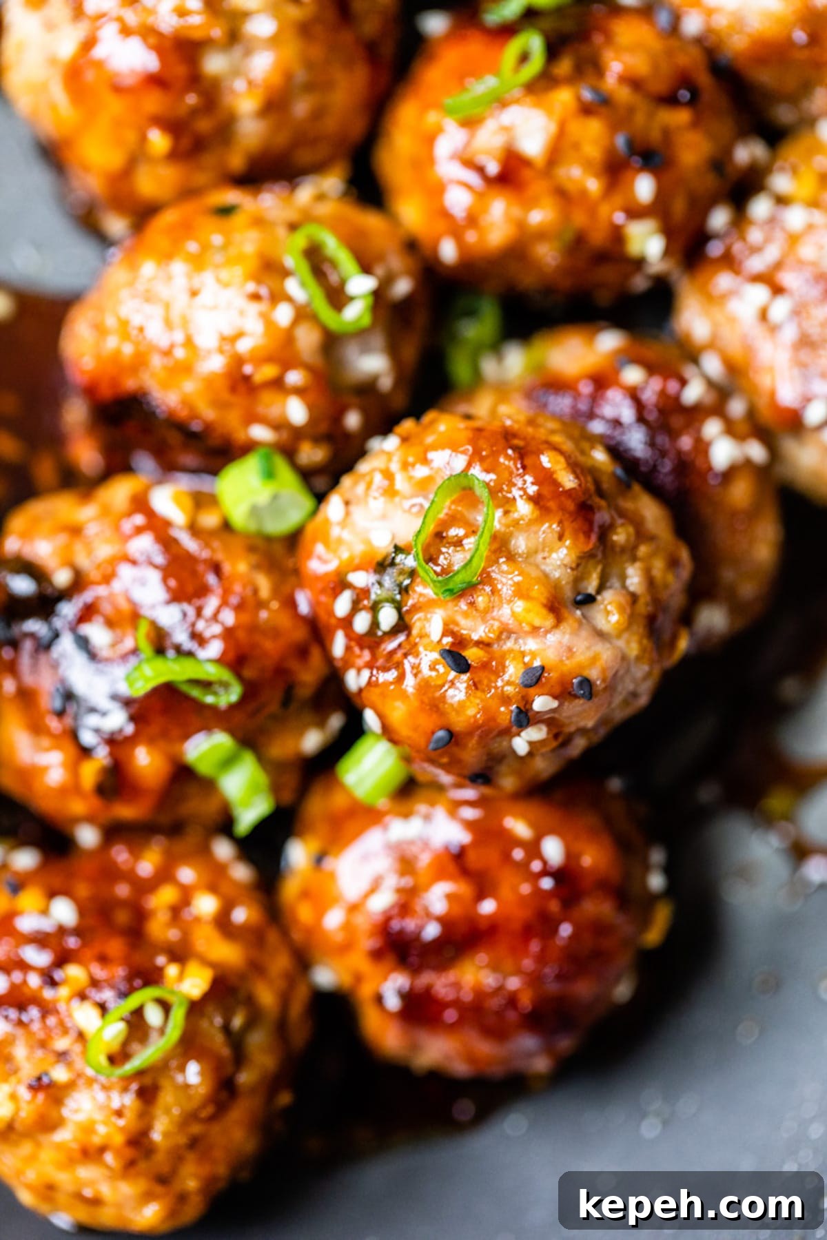 Sticky Teriyaki Pork Meatballs with Ginger and Sesame 7 close up of pork meatballs topped with sesame seeds and green onions