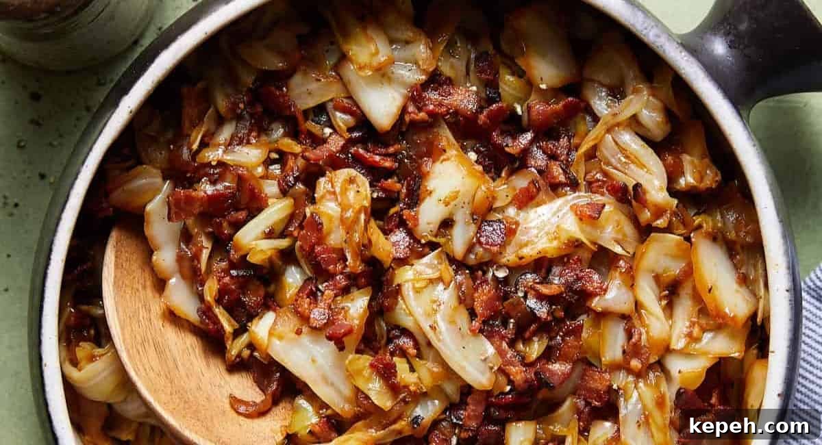 Overhead image of fried cabbage with bacon and onions in black dish.