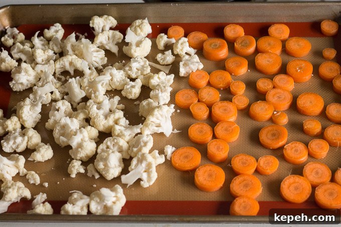 cut up cauliflower and carrots on a sheet pan