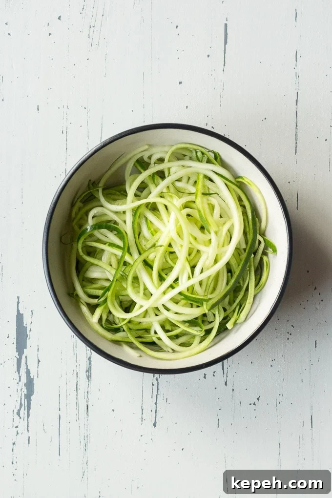 top down view of zucchini noodles in a bowl on an off-white background
