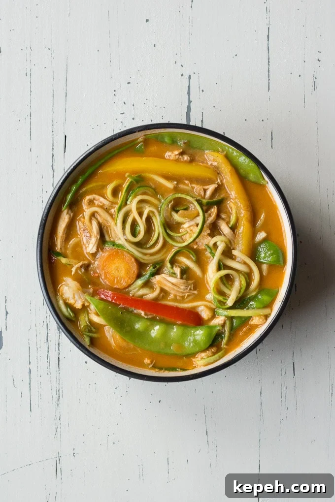 top down view of chicken curry zoodle bowl on an off-white background