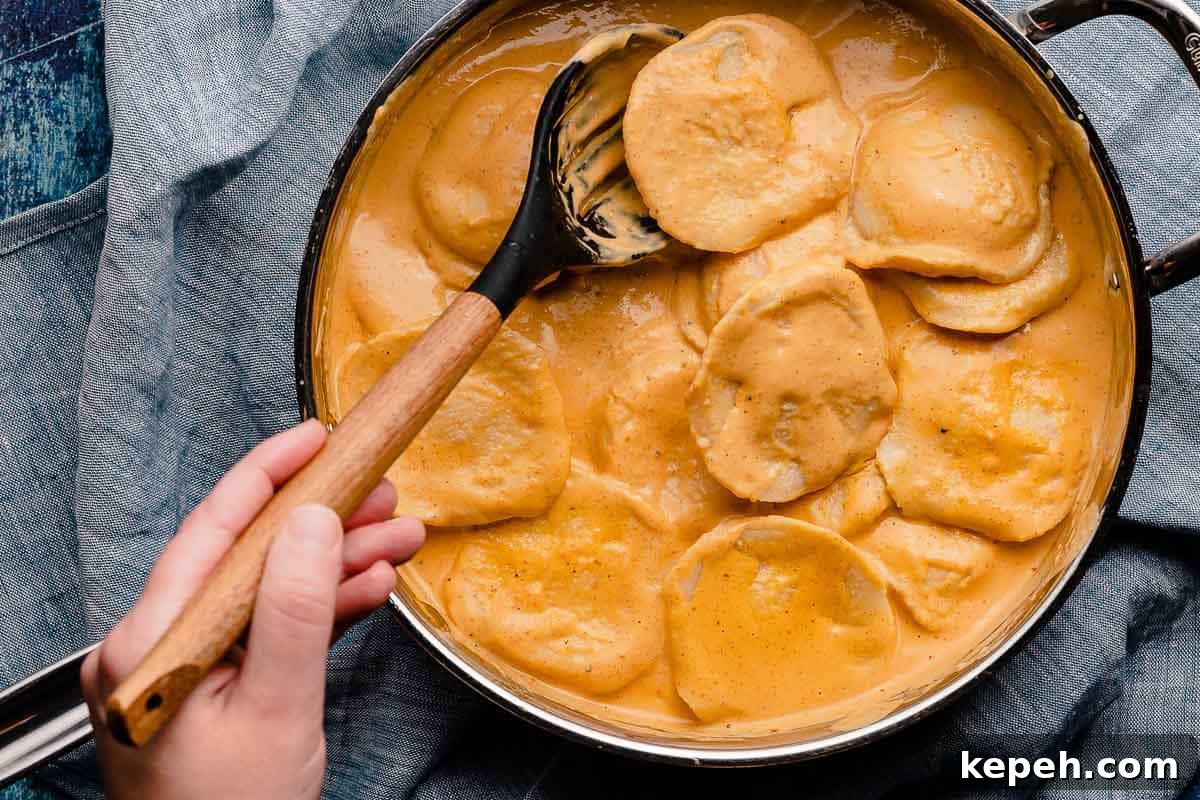 spoon mixing ravioli and pumpkin cream sauce together