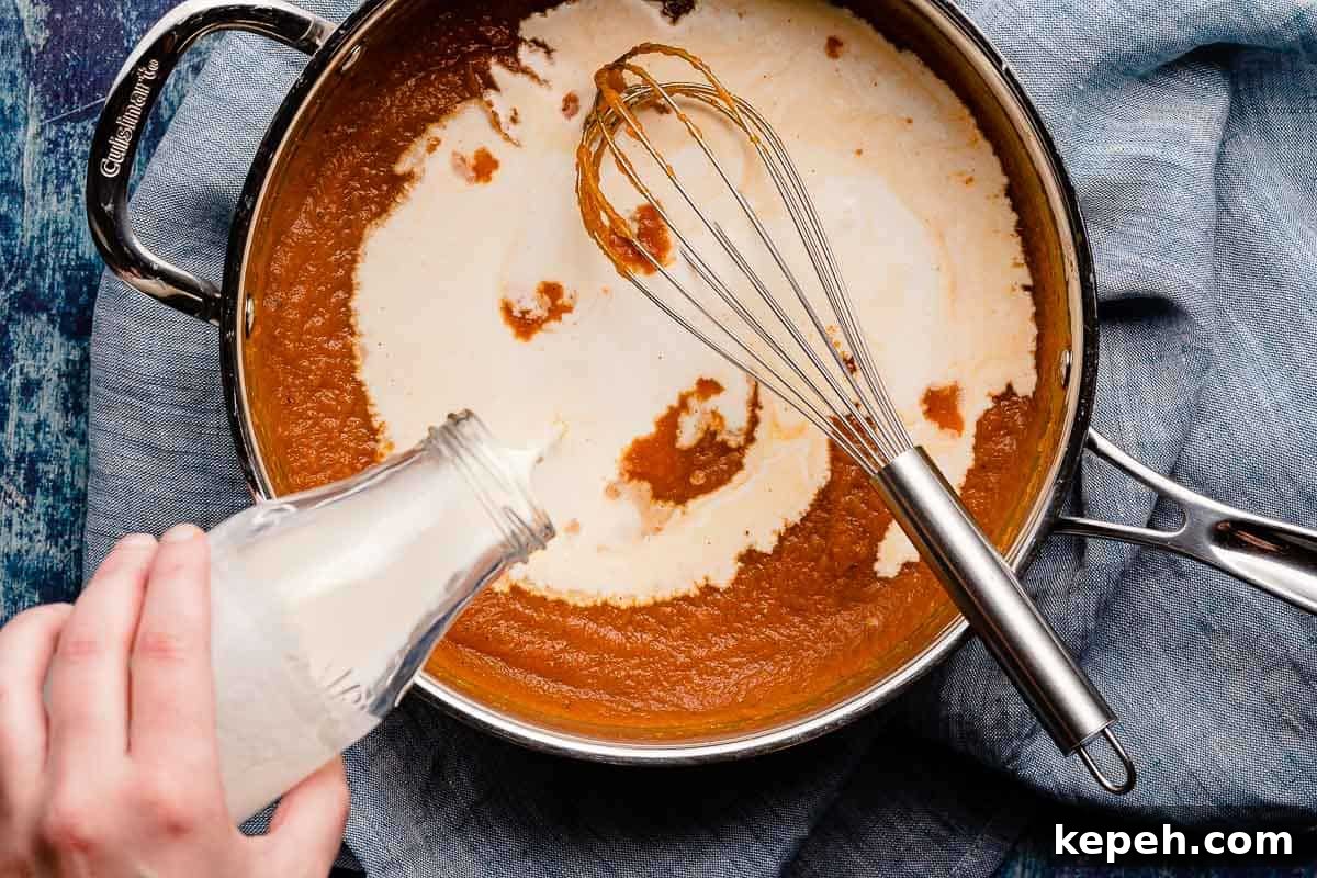 cream being poured into pan with pumpkin mixture inside