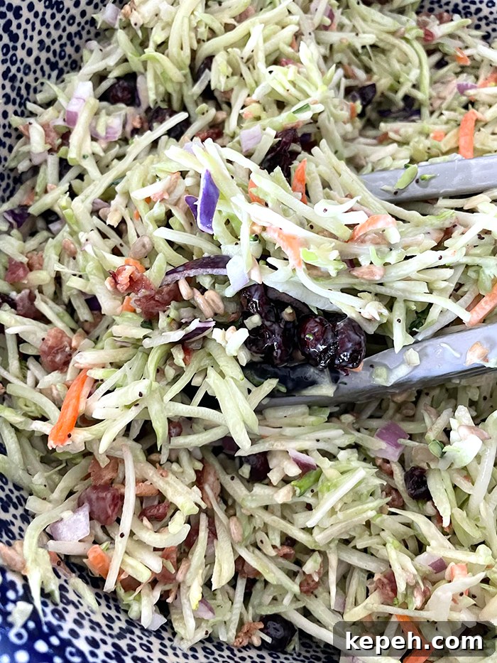 Crunchy Broccoli Slaw with Creamy Dijon Dressing 2 A dark blue and white bubble patterned large Polish pottery bowl with broccoli slaw salad and tongs inserted into the salad from the right.