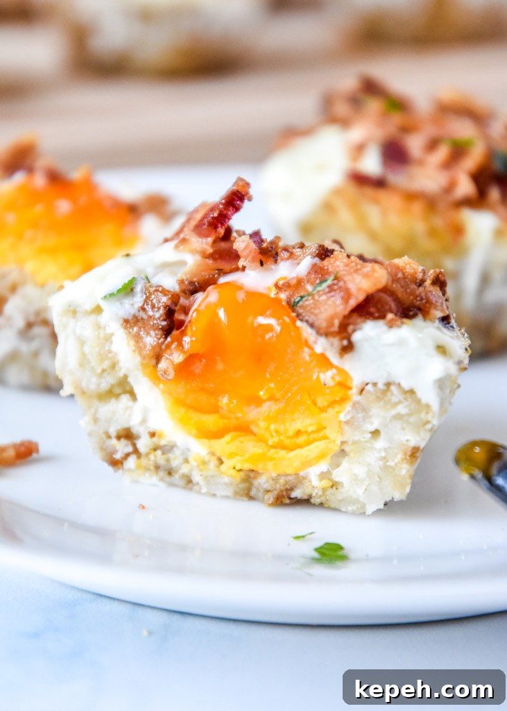 Tater Tot Crust Baked Egg Cups: Crispy Potato Breakfast Cups 2 Tater Tot Crust Baked Egg Muffins on a plate cut in half showing the yolk inside.