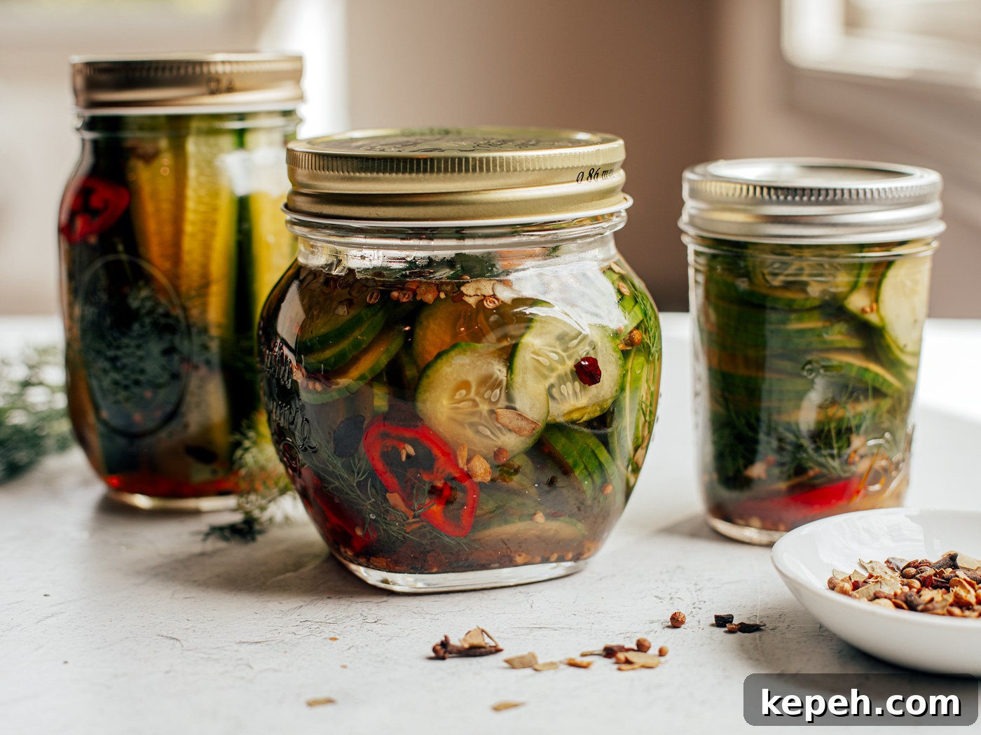 Quick Refrigerator Pickles: Crisp No-Cook Dill Recipe 6 Differently sized jars of refrigerator pickles sitting on countertop.