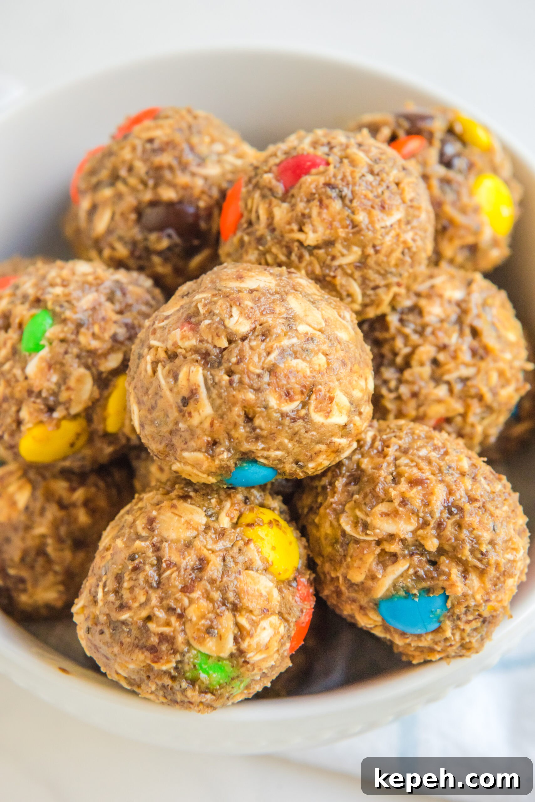 No-Bake M&M Energy Bites: Chocolate Peanut Butter Snack Balls 3 Close up view of No Bake M&M Energy balls in a white bowl.