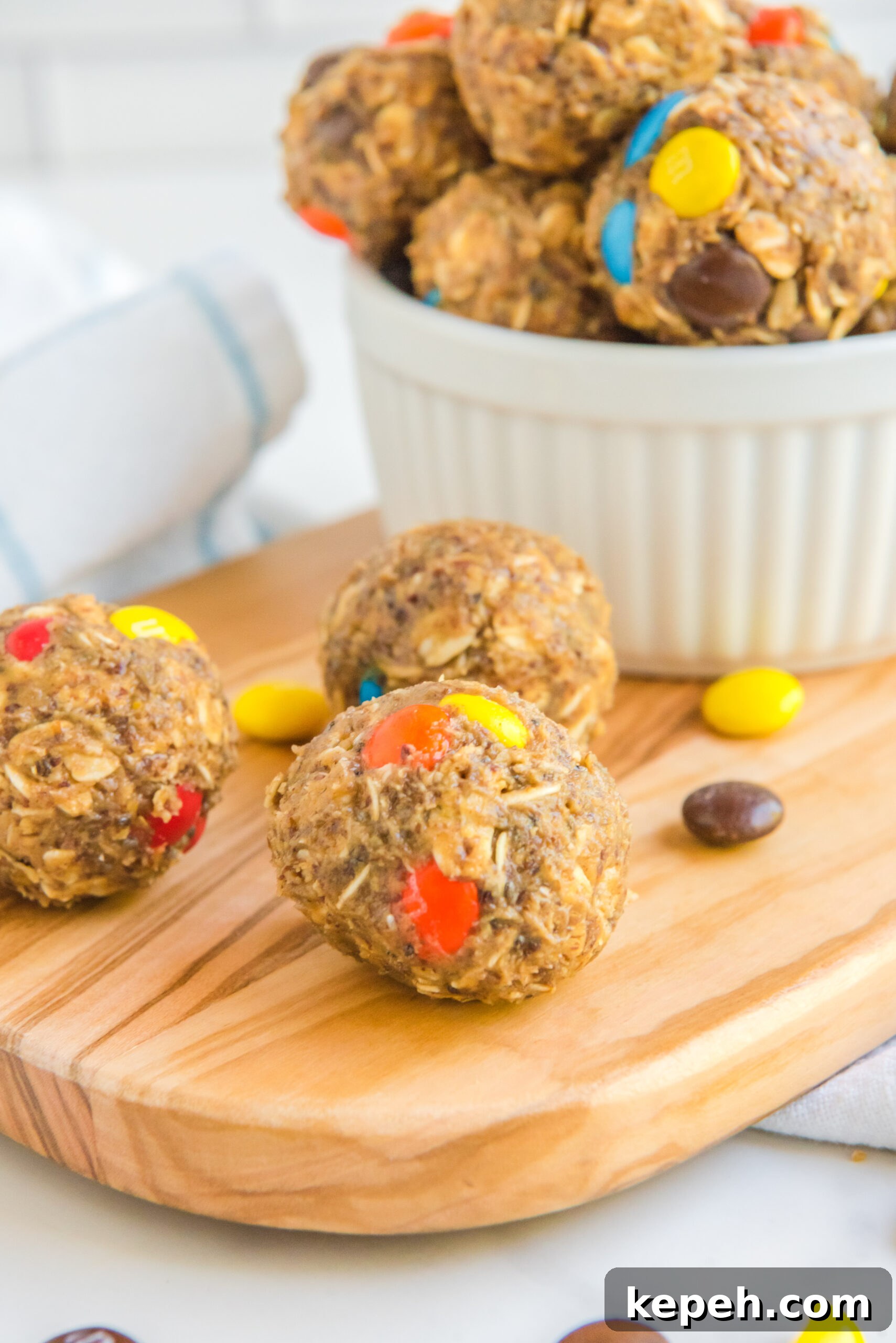 No-Bake M&M Energy Bites: Chocolate Peanut Butter Snack Balls 7 Side view of No Bake M&M Energy Balls on a wooden cutting board.