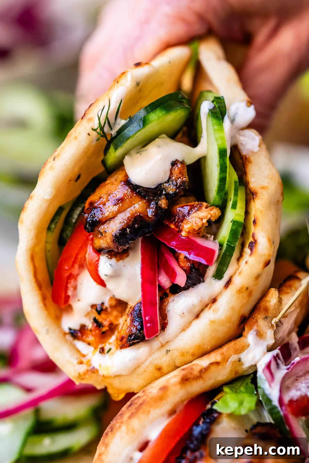 Authentic Chicken Shawarma Recipe: Juicy Middle Eastern Wraps 5 hand holding chicken shawarma in naan with cucumber, onion, and garlic sauce.