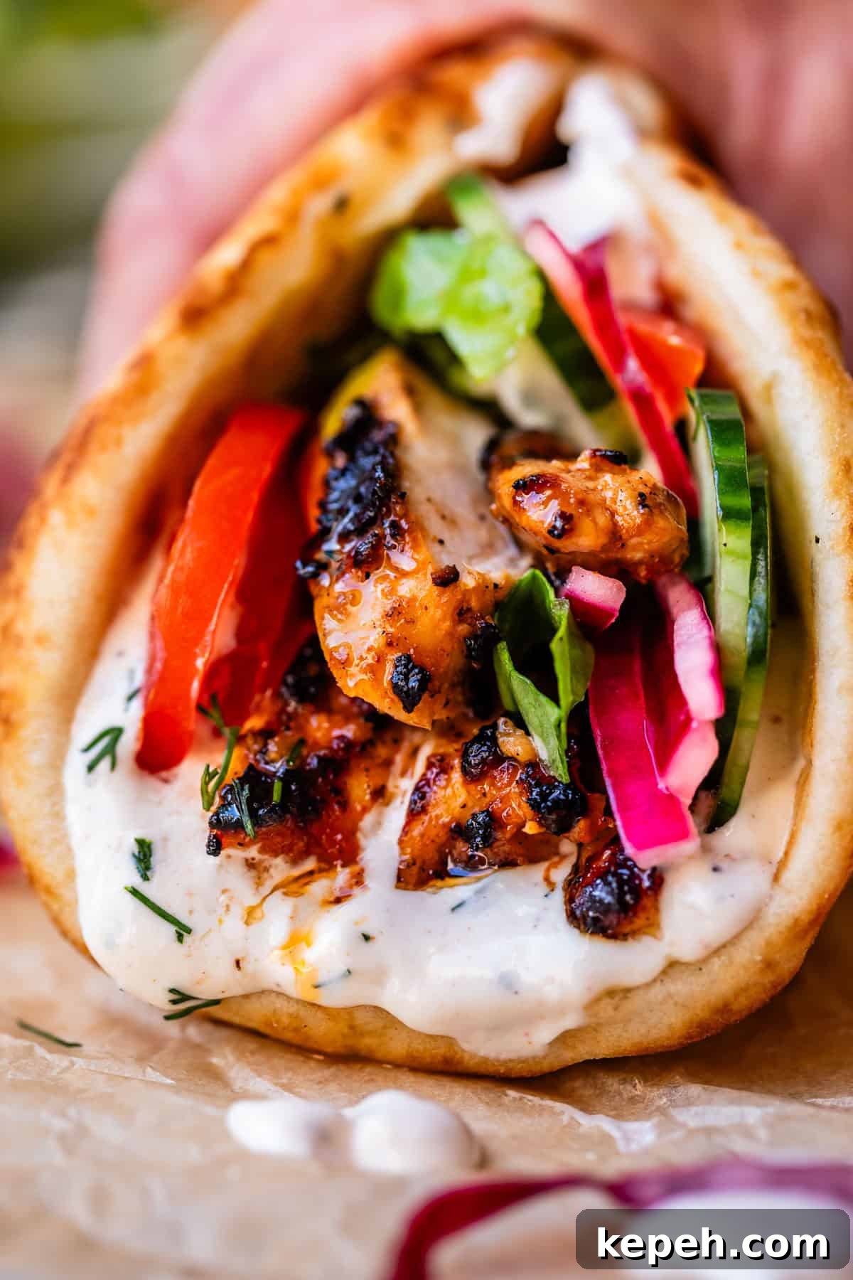Authentic Chicken Shawarma Recipe: Juicy Middle Eastern Wraps 7 hand holding chicken shawarma in naan with cucumber, onion, and garlic sauce.