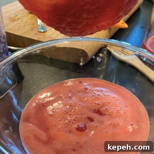 Refreshingly Tart Watermelon Lime Popsicles Recipe 3 straining watermelon juice with large mesh strainer over glass bowl
