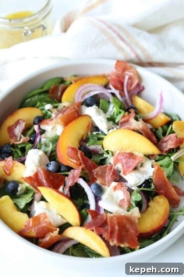 peach burrata salad in large white bowl with gold fork