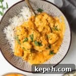 Chicken korma curry on top of rice in a bowl, with more curry and rice on the side.