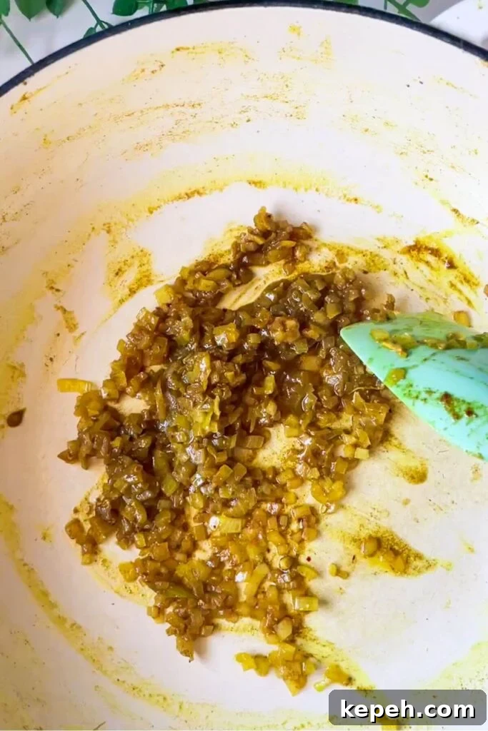 Spatula stirring diced onion in a pan.