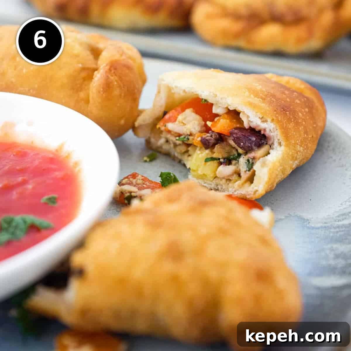 Panzerotti (mini calzone pizza with tuna & red peppers) | www.cookeatworld.com Panzerotti sits on a plate with the filling on show of olives, tuna, egg and red pepper alongside a small dish of tomato sauce