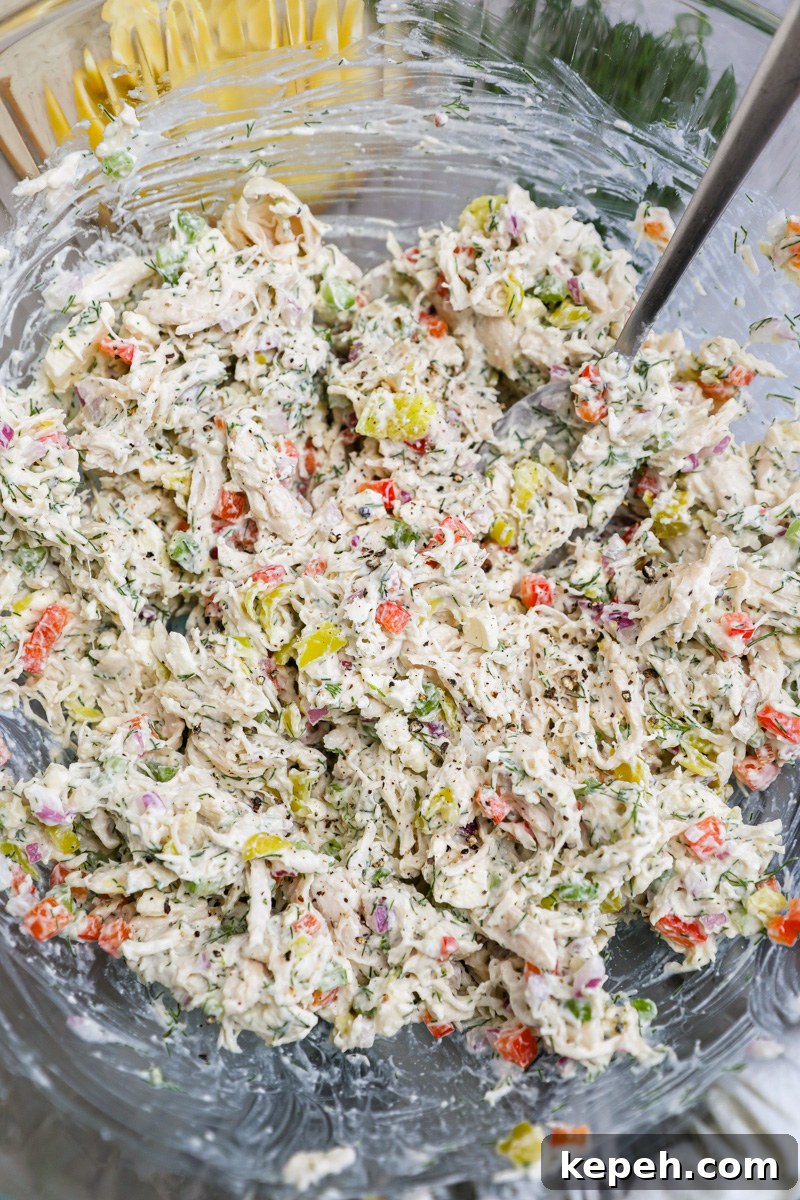 A large clear mixing bowl filled with freshly made feta chicken salad