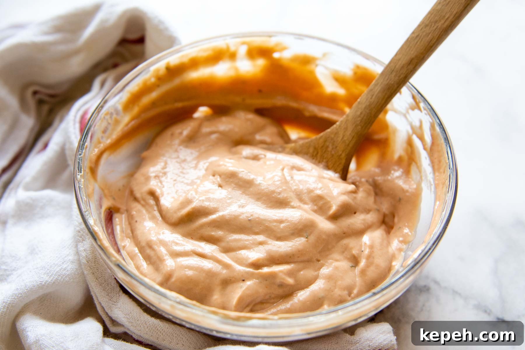 5-Minute BBQ Ranch Sauce & Dressing Recipe 5 a glass bowl with bbq ranch sauce inside and towel laying next to it.