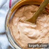 5-Minute BBQ Ranch Sauce & Dressing Recipe 6 overhead shot of barbeque ranch with a wooden spoon in bowl.