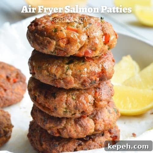 air fryer salmon patties stacked on a white plate with lemon wedges on the background