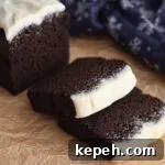 Gluten-Free Gingerbread Loaf Recipe That Delights 12 side view of sliced gingerbread loaf on brown paper with blue snowflake towel in the background.
