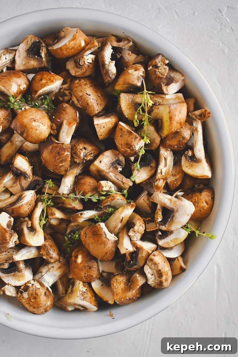 Mushrooms, tossed with olive oil, seasoning, garlic, and thyme, before roasting.